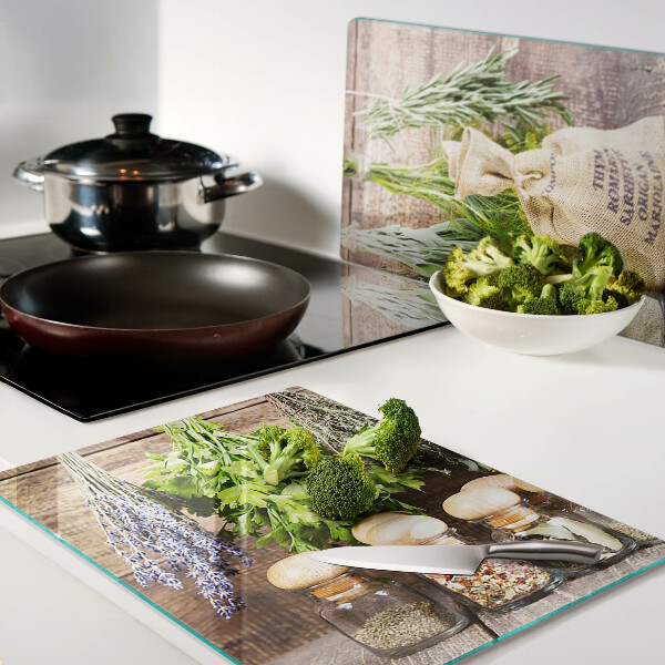 Tagliere in vetro con stampa di erbe e spezie su sfondo di legno