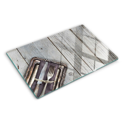 Tagliere in vetro con posate rustiche su sfondo di legno