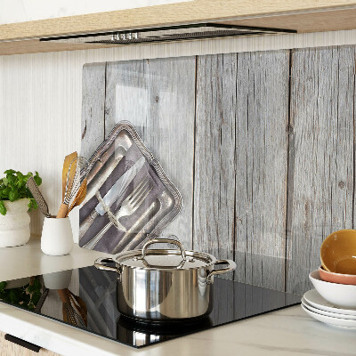 Tagliere in vetro con posate rustiche su sfondo di legno