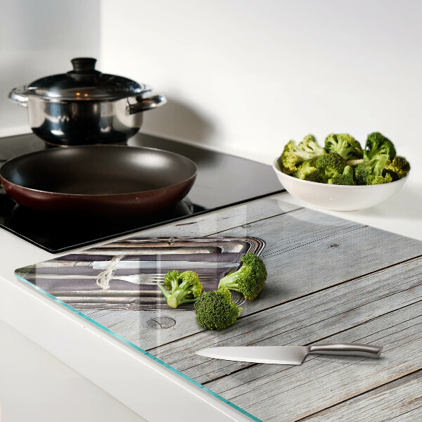 Tagliere in vetro con posate rustiche su sfondo di legno