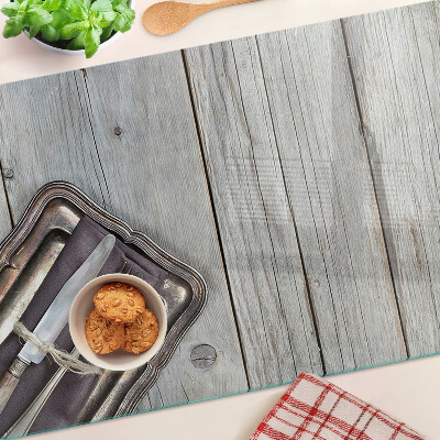 Tagliere in vetro con posate rustiche su sfondo di legno