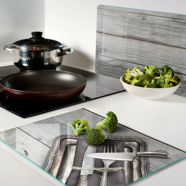 Tagliere in vetro con posate rustiche su sfondo di legno