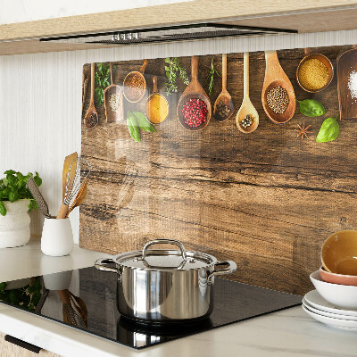 Tagliere in vetro temperato con decorazione di spezie ed erbe su sfondo di legno