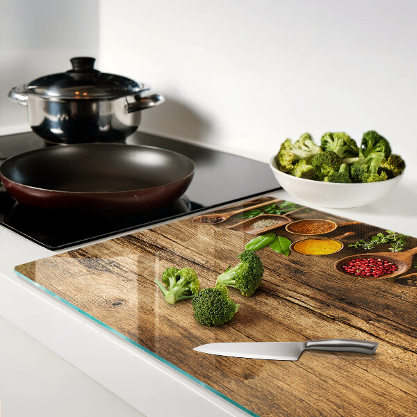 Tagliere in vetro temperato con decorazione di spezie ed erbe su sfondo di legno