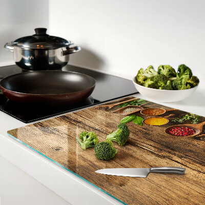 Tagliere in vetro temperato con decorazione di spezie ed erbe su sfondo di legno