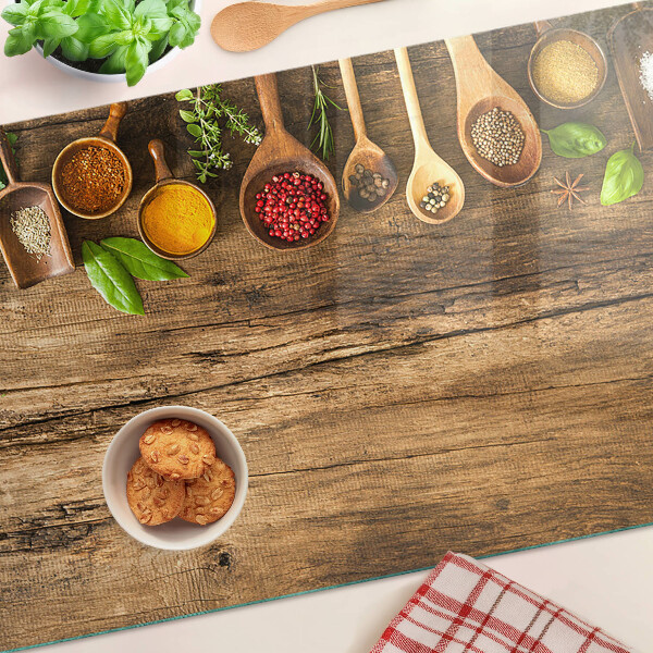 Tagliere in vetro temperato con decorazione di spezie ed erbe su sfondo di legno
