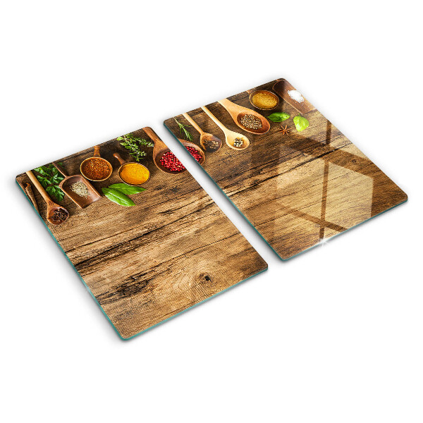 Tagliere in vetro temperato con decorazione di spezie ed erbe su sfondo di legno
