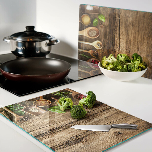 Tagliere in vetro temperato con decorazione di spezie ed erbe su sfondo di legno