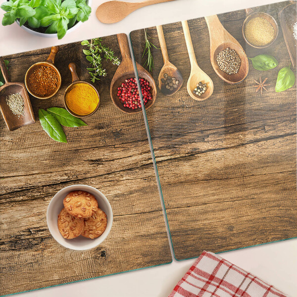 Tagliere in vetro temperato con decorazione di spezie ed erbe su sfondo di legno