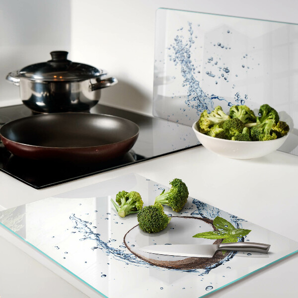 Tagliere in vetro con stampa a tema cocco immerso in acqua con foglie di menta