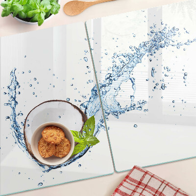 Tagliere in vetro con stampa a tema cocco immerso in acqua con foglie di menta
