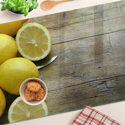 Tagliere in vetro con stampa di limoni su sfondo di legno