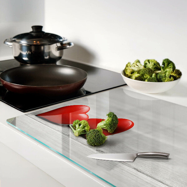 Tagliere in vetro con motivo di cuori rossi su sfondo di legno