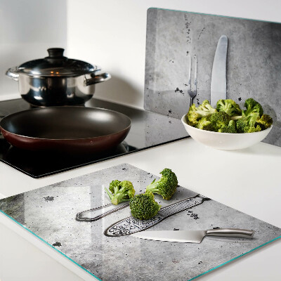 Tagliere in vetro temperato con motivo di posate su sfondo effetto cemento