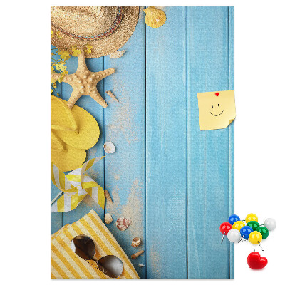 Bacheca di sughero con stampa di accessori estivi su sfondo di legno blu