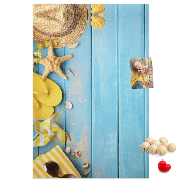 Bacheca di sughero con stampa di accessori estivi su sfondo di legno blu