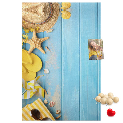 Bacheca di sughero con stampa di accessori estivi su sfondo di legno blu