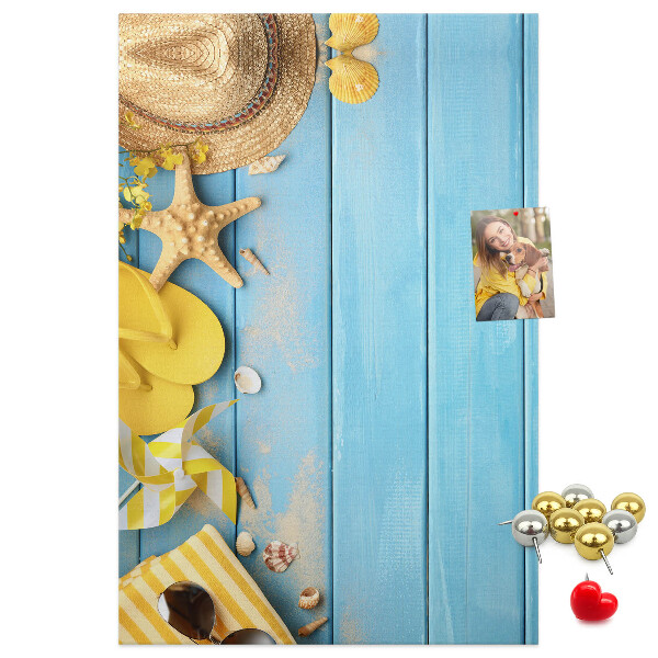 Bacheca di sughero con stampa di accessori estivi su sfondo di legno blu