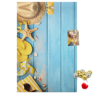 Bacheca di sughero con stampa di accessori estivi su sfondo di legno blu
