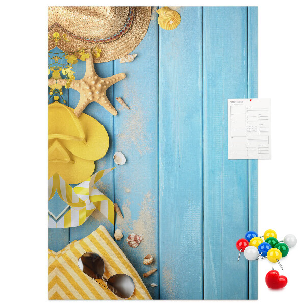 Bacheca di sughero con stampa di accessori estivi su sfondo di legno blu