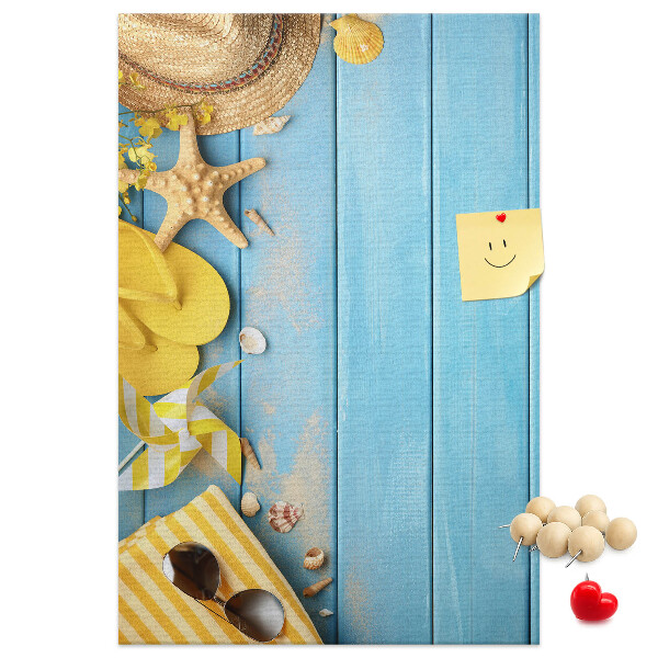 Bacheca di sughero con stampa di accessori estivi su sfondo di legno blu