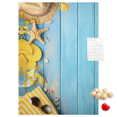 Bacheca di sughero con stampa di accessori estivi su sfondo di legno blu
