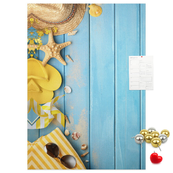 Bacheca di sughero con stampa di accessori estivi su sfondo di legno blu