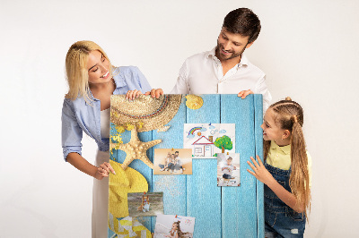 Bacheca di sughero con stampa di accessori estivi su sfondo di legno blu