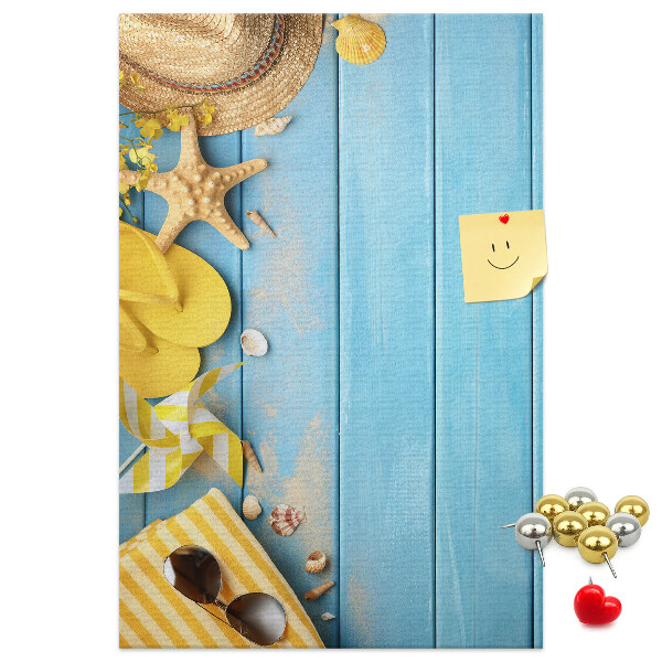 Bacheca di sughero con stampa di accessori estivi su sfondo di legno blu