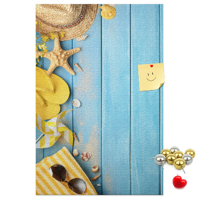 Bacheca di sughero con stampa di accessori estivi su sfondo di legno blu