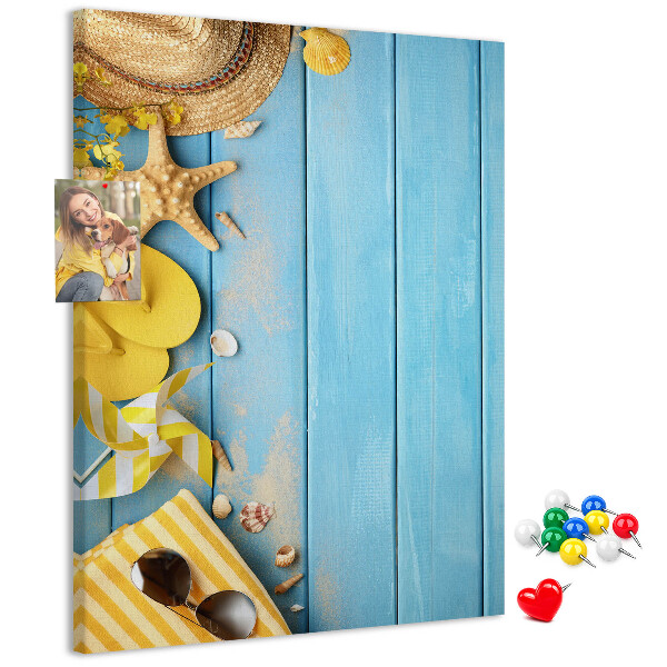 Bacheca di sughero con stampa di accessori estivi su sfondo di legno blu