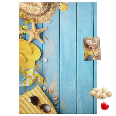 Bacheca di sughero con stampa di accessori estivi su sfondo di legno blu