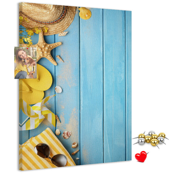 Bacheca di sughero con stampa di accessori estivi su sfondo di legno blu