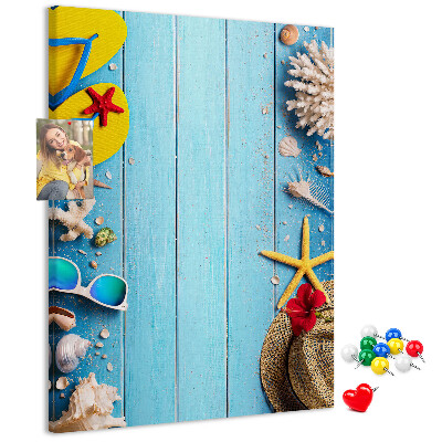 Bacheca di sughero con accessori estivi su sfondo di legno blu