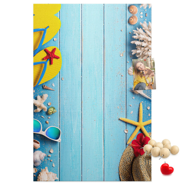 Bacheca di sughero con accessori estivi su sfondo di legno blu