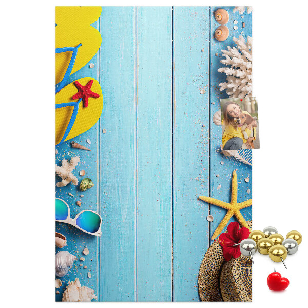 Bacheca di sughero con accessori estivi su sfondo di legno blu