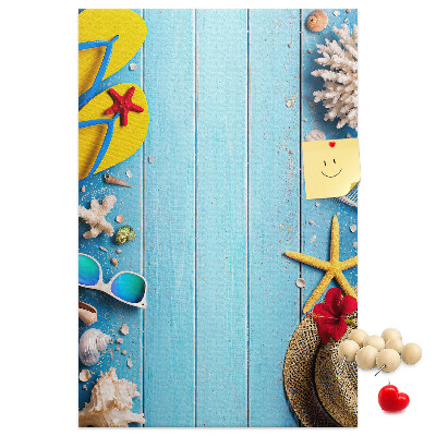 Bacheca di sughero con accessori estivi su sfondo di legno blu