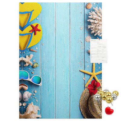Bacheca di sughero con accessori estivi su sfondo di legno blu