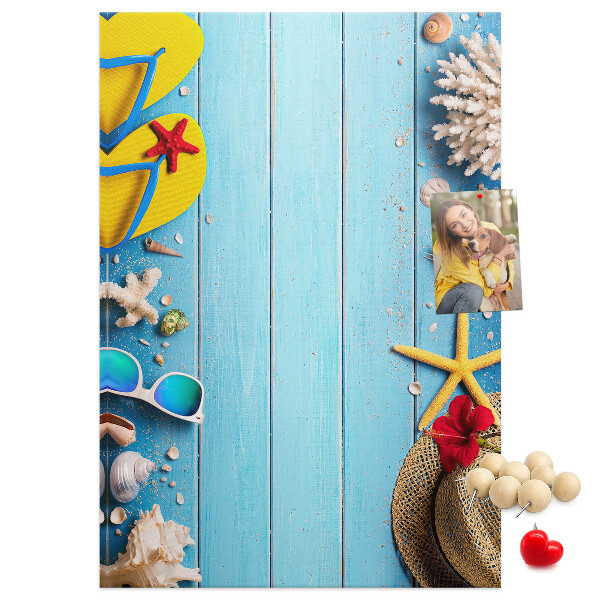 Bacheca di sughero con accessori estivi su sfondo di legno blu