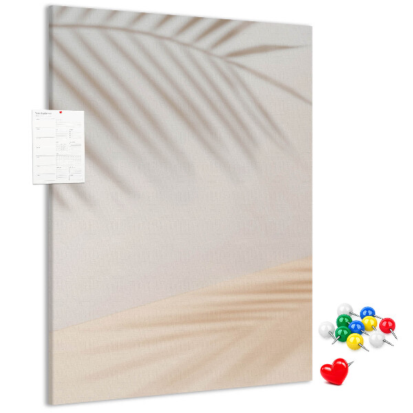 Bacheca di sughero con delicate ombre di palme su sfondo chiaro