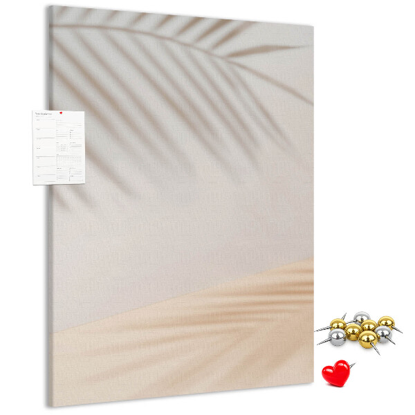 Bacheca di sughero con delicate ombre di palme su sfondo chiaro