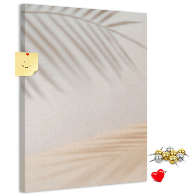 Bacheca di sughero con delicate ombre di palme su sfondo chiaro