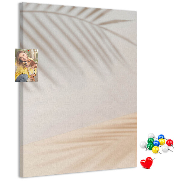 Bacheca di sughero con delicate ombre di palme su sfondo chiaro