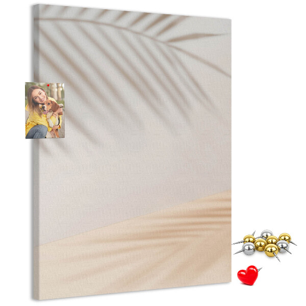 Bacheca di sughero con delicate ombre di palme su sfondo chiaro