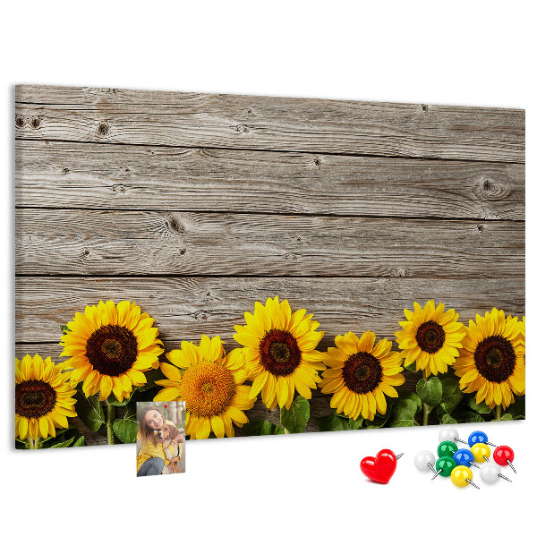 Lavagna di sughero con stampa di girasoli su sfondo di assi di legno