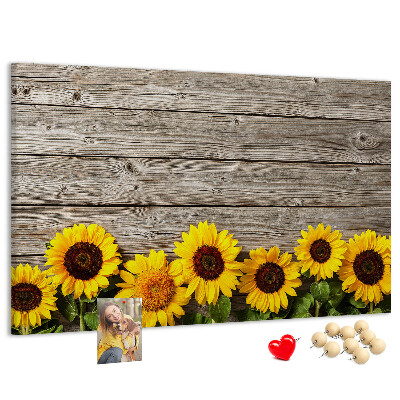 Lavagna di sughero con stampa di girasoli su sfondo di assi di legno