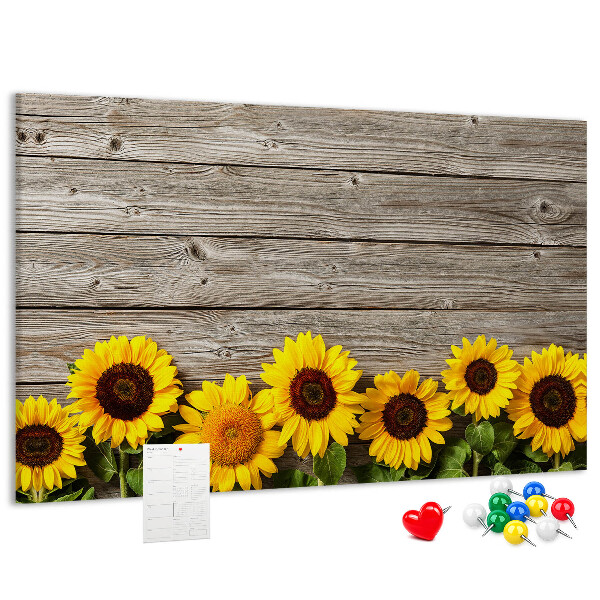 Lavagna di sughero con stampa di girasoli su sfondo di assi di legno