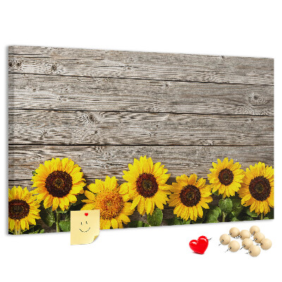 Lavagna di sughero con stampa di girasoli su sfondo di assi di legno