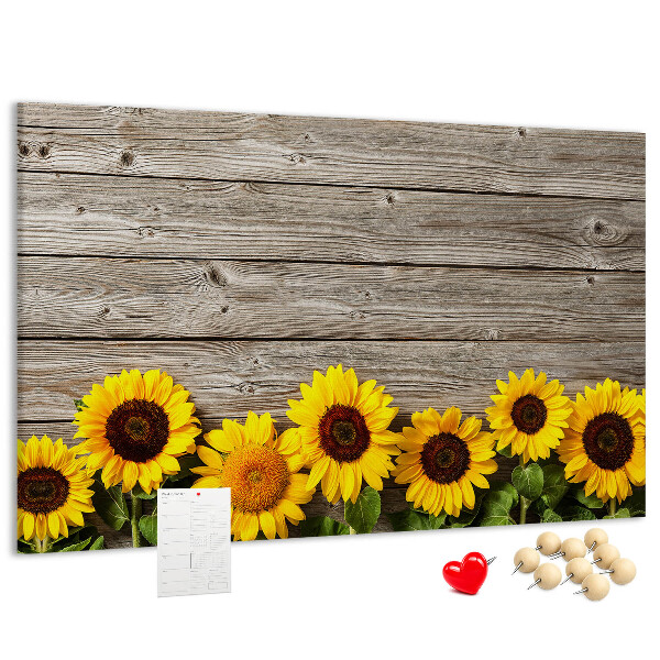 Lavagna di sughero con stampa di girasoli su sfondo di assi di legno