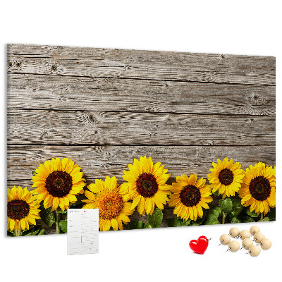Lavagna di sughero con stampa di girasoli su sfondo di assi di legno
